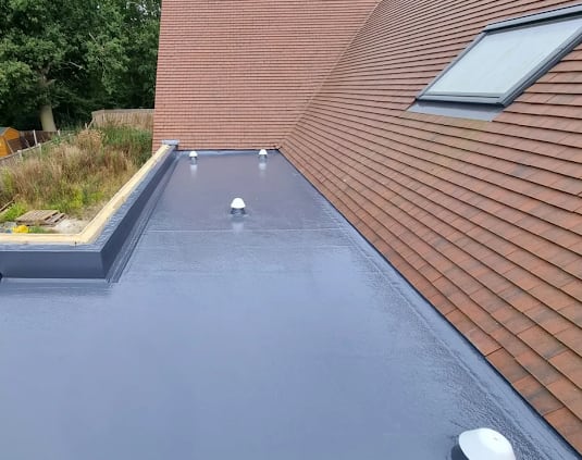 Finished grey flat roof around a pitched roof junction with neat upstands and outlets in Reading